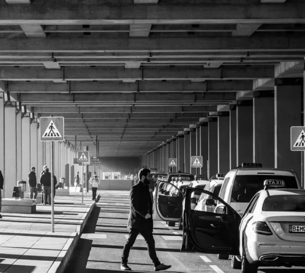 Burlington airport taxi scene with passengers, taxis, and signage, emphasizing reliable transportation services in Burlington, VT.